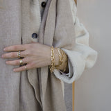 Pols met vijf gouden armbanden van Melanie Pigeaud, waaronder de getekende chain armband in 14K goud.