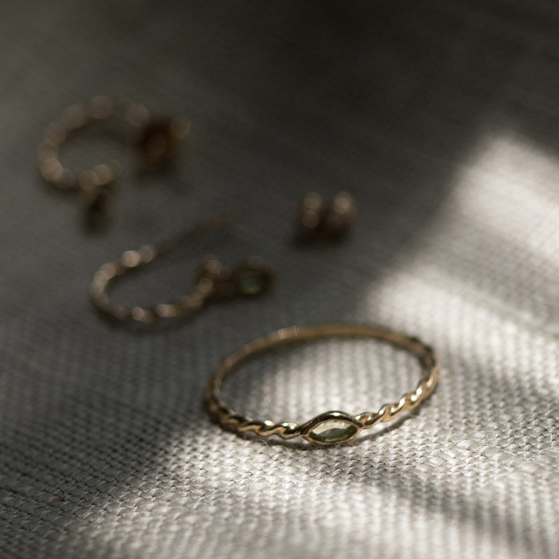Melanie Pigeaud ring met peridot steen in 9 karaat gepresenteerd op stof