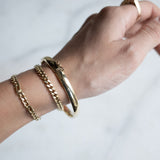 Pols met drie gouden armbanden van Melanie Pigeaud, waaronder de Slave armband 14k goud