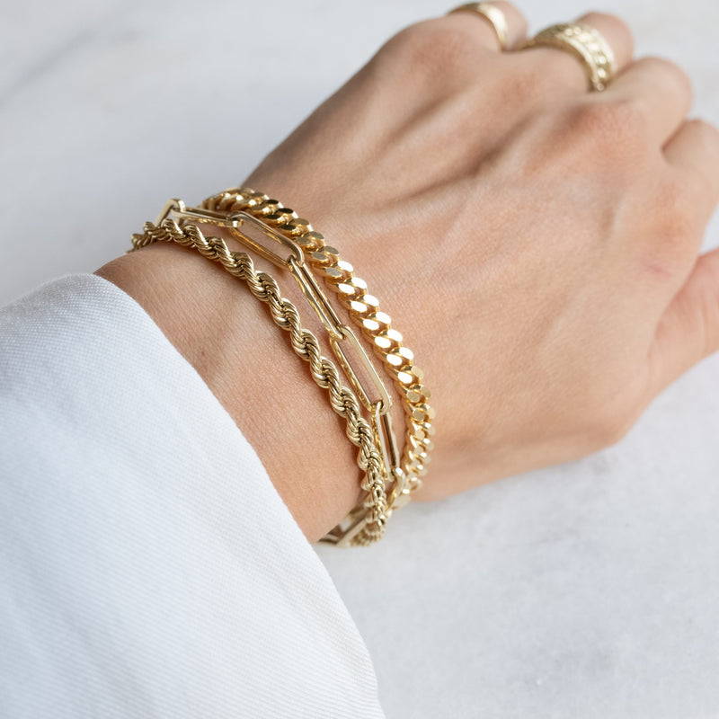 Pols met drie gouden armbanden van Melanie Pigeaud, waaronder de Wired armband 14k goud.